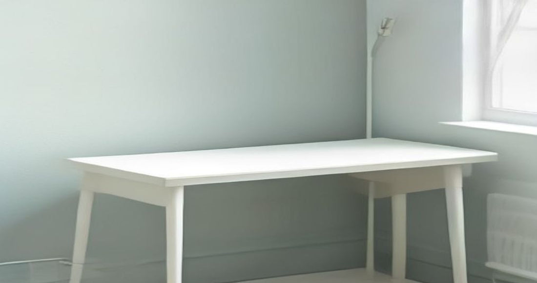 A clean white desk against a pale mint wall with a single cable running neatly to the outlet.