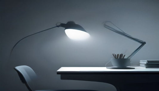 An adjustable desk lamp casting a single pool of soft light onto a minimal desk in a cool, dim blue-grey room.