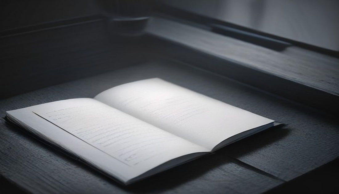An open blank notebook and a capped pen resting alone in the clear center of an otherwise empty dark desk, lit by dramatic side light.