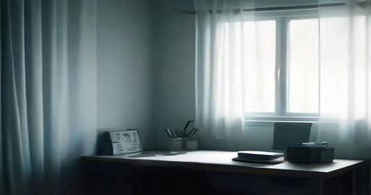 A quiet desk beside a curtained window in soft blue-grey morning light.